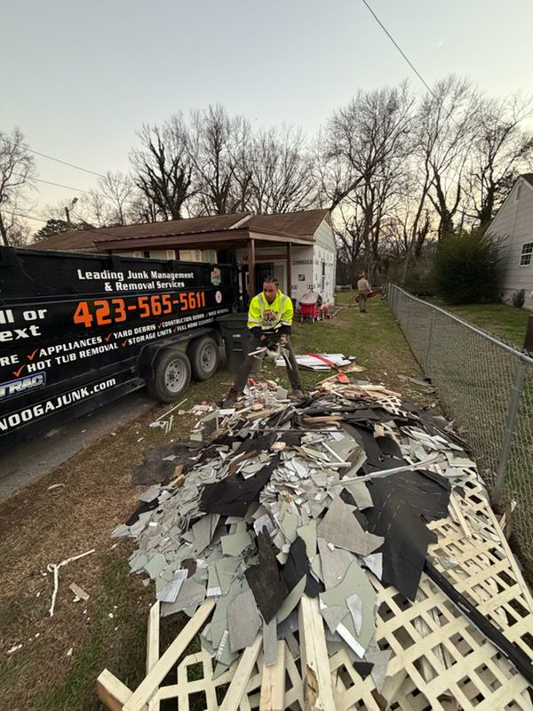 A Nooga Junk team member loading roofing debris into a trailer during a junk removal job in Chattanooga, TN.