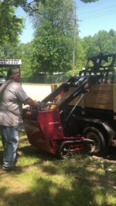 A Bushmasters Tree Care worker using a Toro Dingo compact utility loader to load tree debris onto a trailer in Westland, MI.