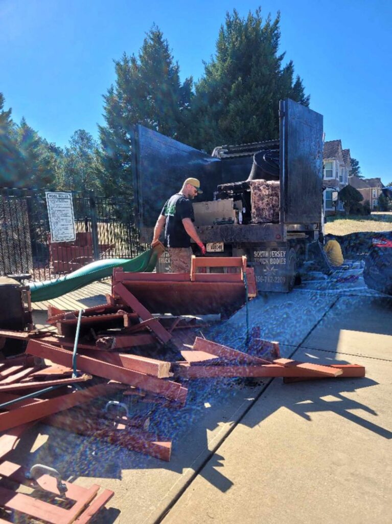A G.I.HAUL ATLANTA worker loading wooden debris into a junk removal truck during a cleanup job in Atlanta, GA.