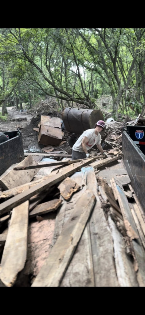 A worker actively loading wooden planks into a dump trailer, performing junk removal for Speedy Scrap Junk Removal LLC in Portage, WI.
