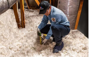 A worker measuring the depth of blown-in attic insulation for Attic Insulation of Memphis in Byhalia, MS.