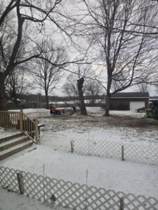 A tree service worker using a tractor with a grapple to move branches for Father and Son Tree Service in Lansing, MI.