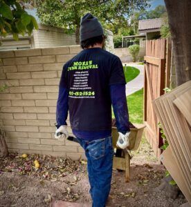 A Mora's Junk Removal & Hauling llc. worker moving debris with a wheelbarrow at a job site in Scottsdale, AZ