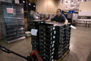 A Securis worker moving pallets stacked with computers and IT equipment in a warehouse in Greensboro, NC