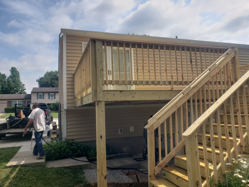 A worker near a newly built wooden deck with stairs attached to a house by A1 Roofing in Scottsdale, AZ