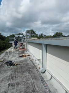 A worker on a commercial building roof, performing installation or repair work for Charleston Exteriors in Charleston, SC.