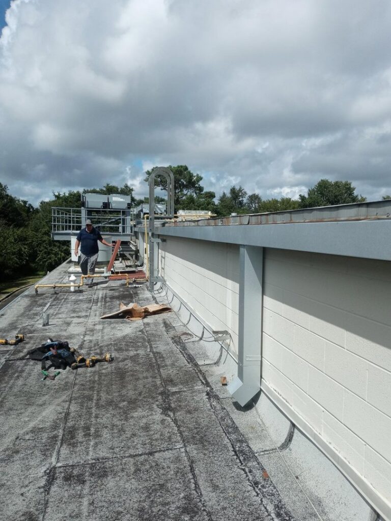 A worker on a commercial building roof, performing installation or repair work for Charleston Exteriors in Charleston, SC.