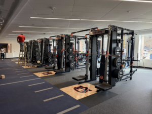 A worker on a ladder performing ceiling repair or installation at a gym by Jack Ellison Painting Contractors Inc. in Montgomery, AL.