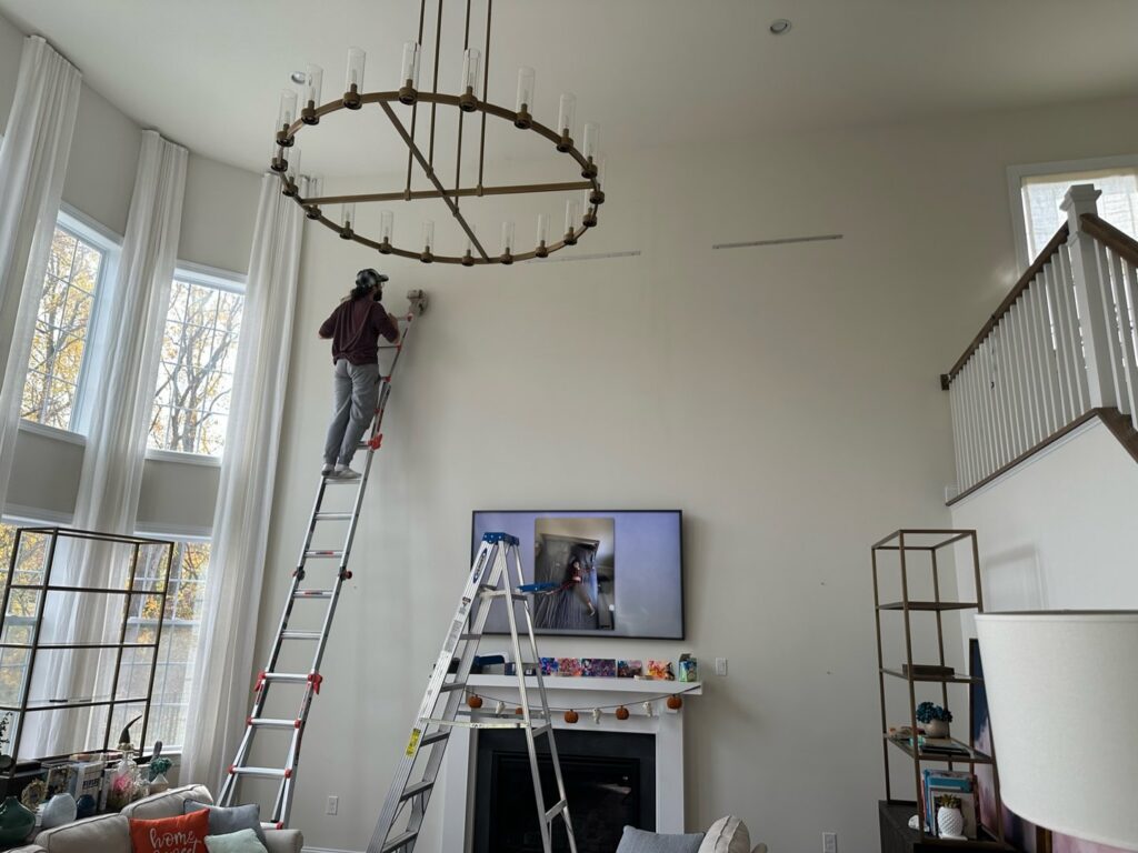 A worker on a ladder performing interior wall work in a living room for Imagine It Home Improvements Co. in Bethlehem, PA.