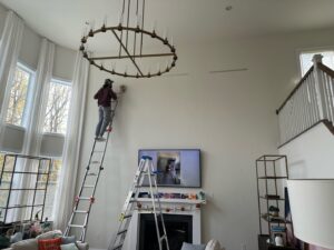A worker on a ladder performing interior wall work in a living room for Imagine It Home Improvements Co. in Bethlehem, PA.