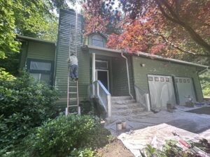 A worker on a ladder painting the house exterior for J&R Buezo Painting Services LLC, providing handyman services in Everett, WA