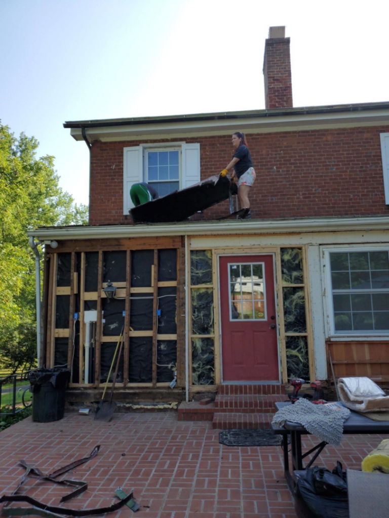 A worker on a ladder performing exterior renovation work on a brick house, demonstrating services by DBB, Inc. in Harrisonburg, VA.