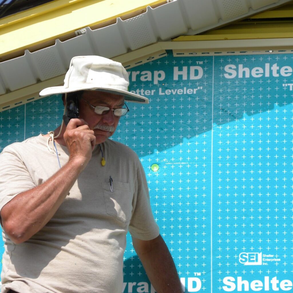 A worker on the phone at a construction job site with house wrap in the background by B & L Builders in Jonesborough, TN