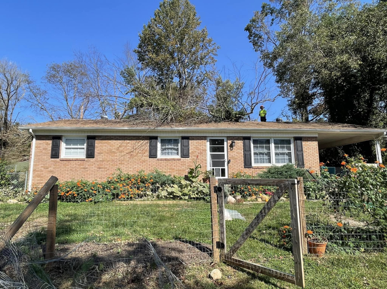A tree service worker on a roof removing a fallen tree branch for A Cut Above Tree and Crane in Carrollton, VA.