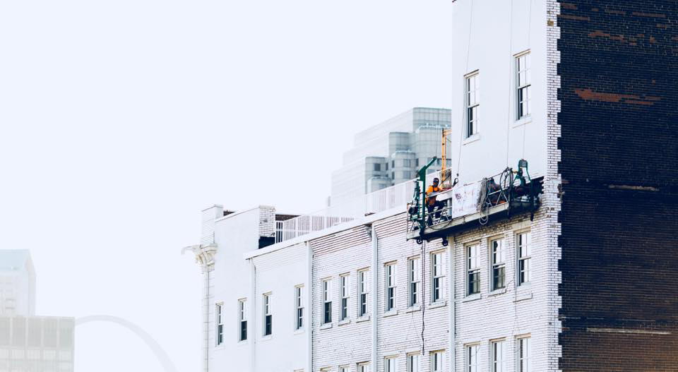 A worker on a suspended scaffold performing exterior brick repair on a building for B & K Tuckpointing Company in Saint Louis, MO.