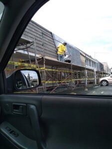 A worker on scaffolding performing exterior renovation work on a building for Unique Construction Services in Knoxville, TN