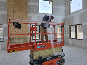 A worker on a scissor lift preparing a room for renovation and painting by Painting Pros of Knoxville in Knoxville, TN.