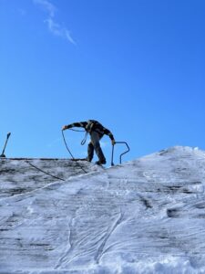 A worker on a snowy roof preparing for or performing snow removal services for Alaskan Residential Rescue in Anchorage, AK.