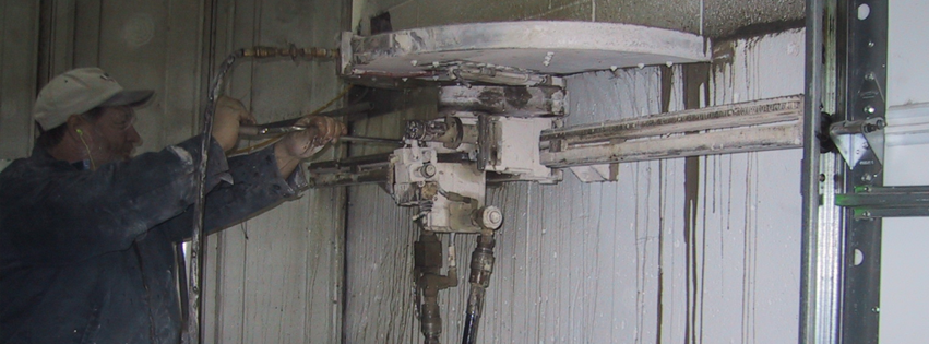 A worker operating a concrete cutting and drilling machine on a wall for Capitol Drilling & Sawing Of Kentucky in Elizabethtown, KY.