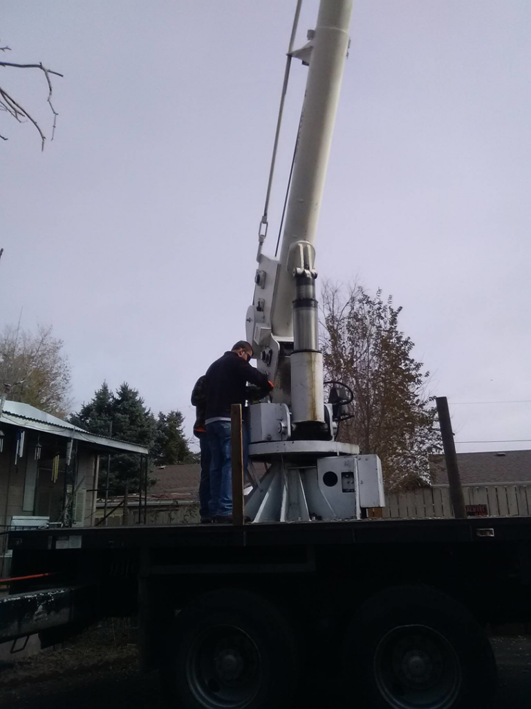 A worker operating a crane truck for tree service by A Lifetime Of Quality Tree Care & Landscaping in Thornton, CO.