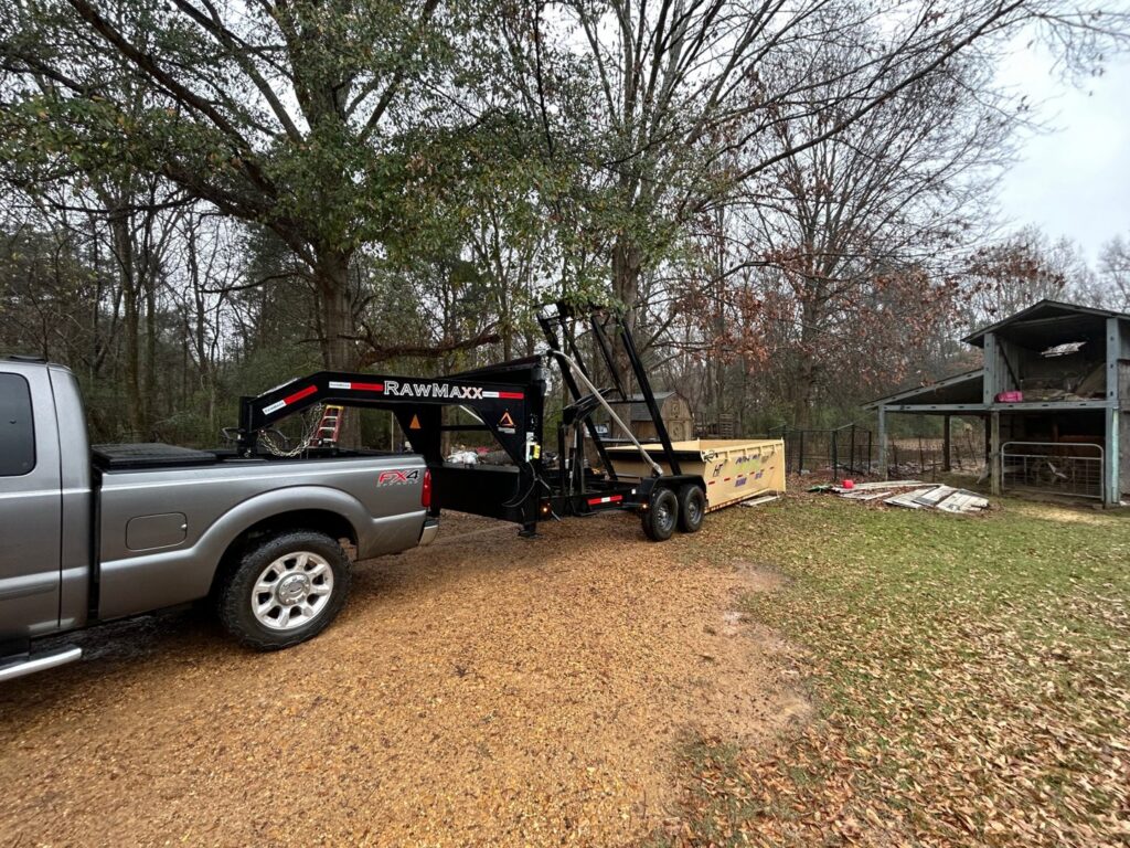 A worker from Curry Dumpster Rentals LLC operating the lift mechanism to deploy a dumpster for junk removal in Southaven, MS.