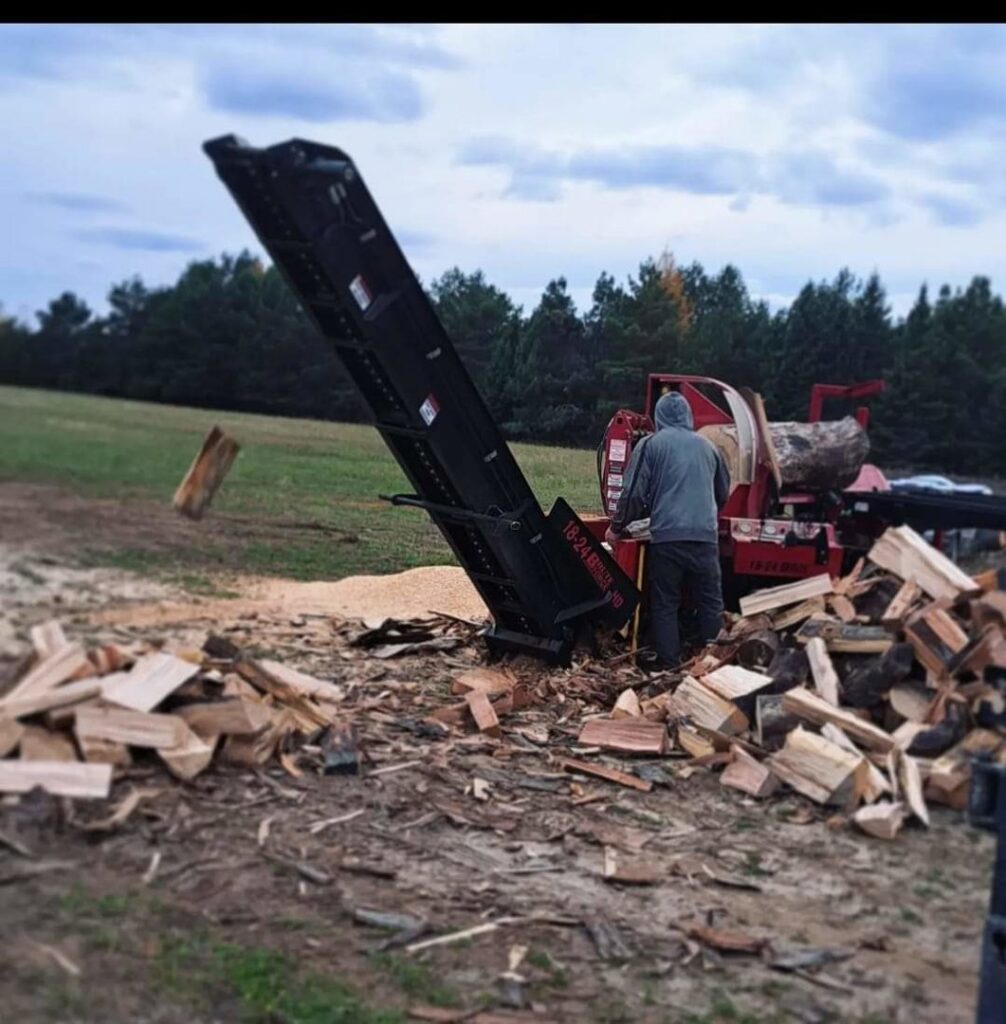 A worker operating a log splitter to process wood, a service provided by Klee Logging & Tree Service Inc. in Green Bay, WI.