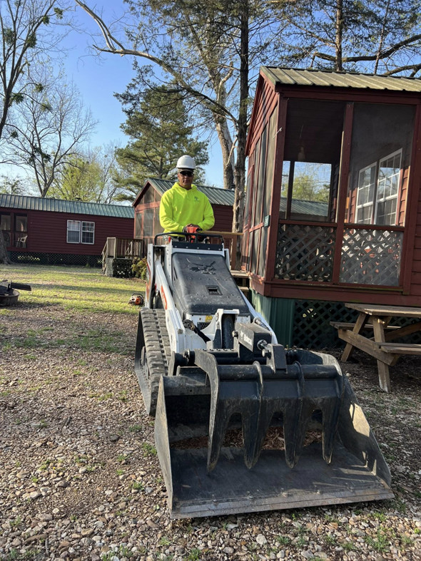A tree service worker operating a Bobcat skid-steer loader for debris removal by Four Seasons Tree Service, LLC in Eufaula, OK