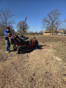 A professional worker operating a powerful stump grinder, creating wood chips on the ground for Garcia's Tree service in Louisville, KY.
