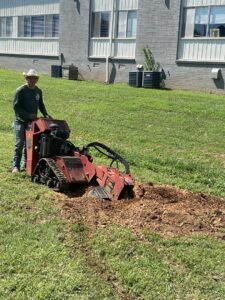 A worker from Mr. Green-Jeans Lawn Service & Tree Service operating a stump grinder to remove a tree stump in Decatur, AL.