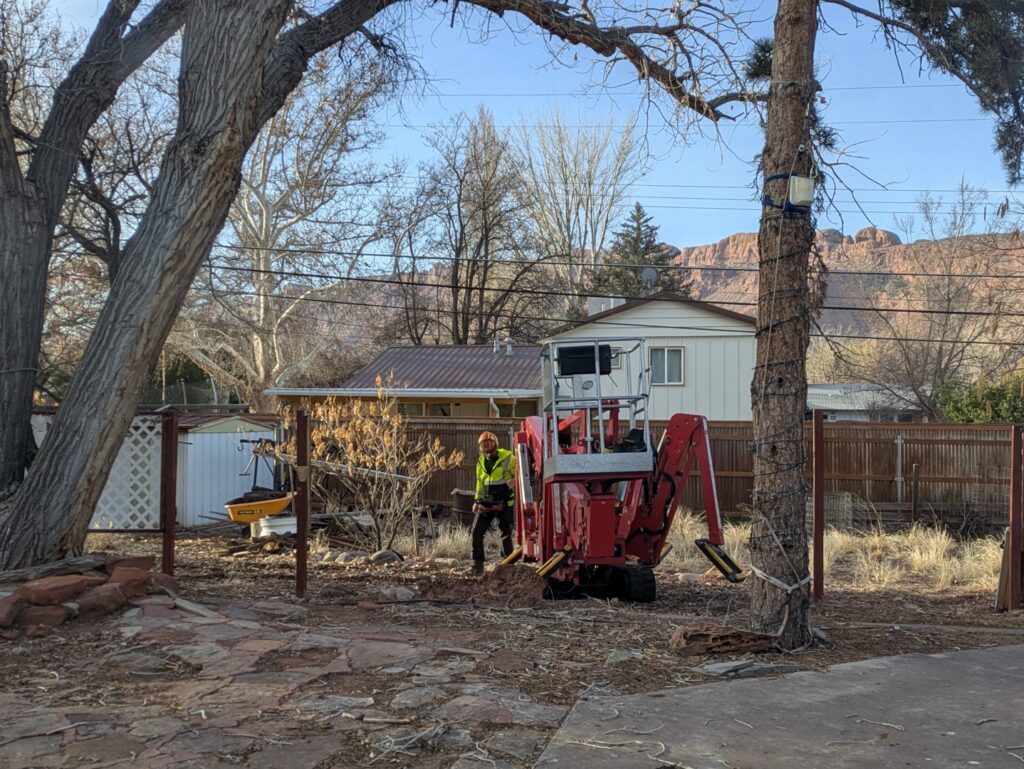 A worker from My Tree Guys, LLC, operating a stump grinder in a backyard in Salt Lake City, UT.