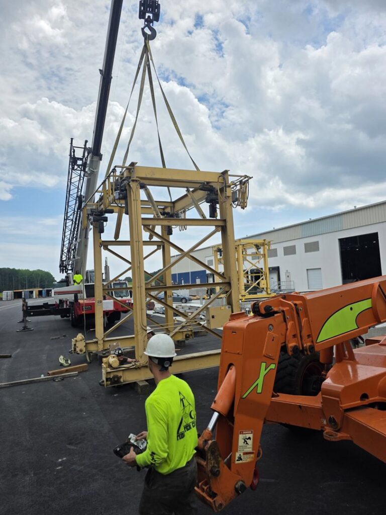 A worker from Tidewater Crane & Contracting overseeing a crane lifting a large metal structure in Virginia Beach, VA