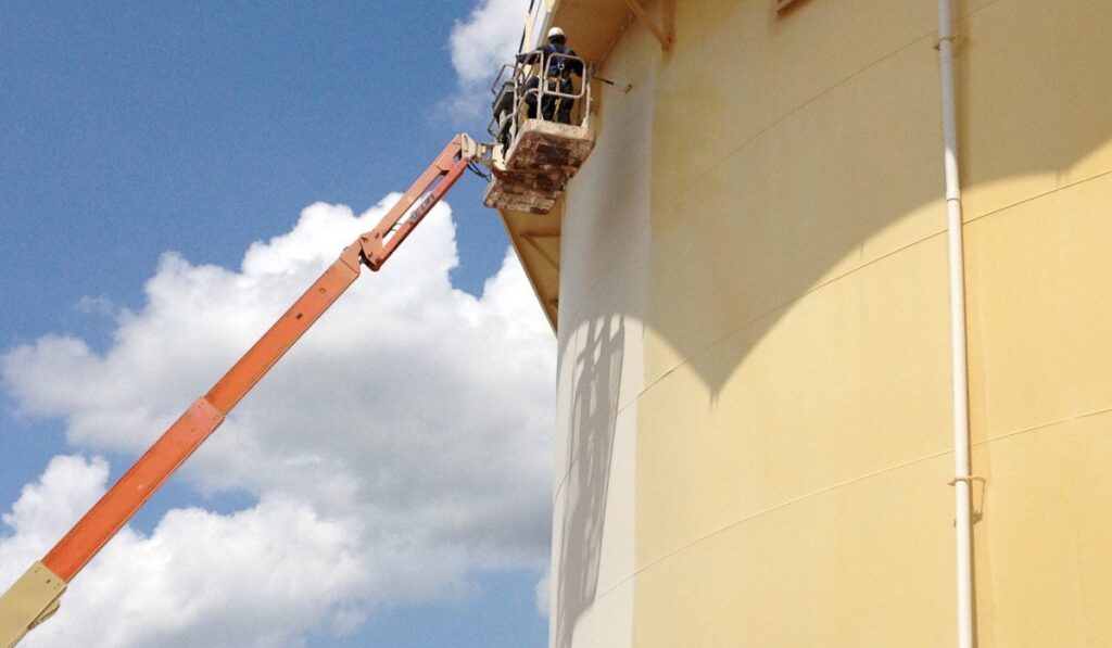A worker in a boom lift painting a large industrial tank for WW Enroughty & Son, Inc. in Richmond, VA.