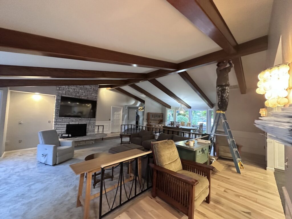 A worker on a ladder painting interior ceiling beams for J&R Buezo Painting Services LLC, providing handyman work in Everett, WA