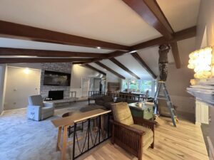 A worker on a ladder painting interior ceiling beams for J&R Buezo Painting Services LLC, providing handyman work in Everett, WA