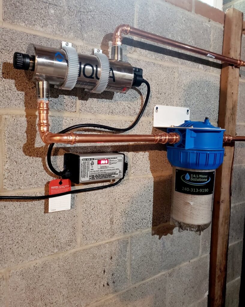 A worker performing plumbing work on a water system next to a company van for S & L Water Solutions in Hagerstown, MD.