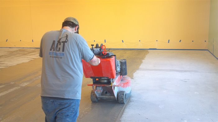 A worker from ACT Restoration operating a floor polishing machine on a concrete floor in Andover, MN.