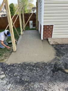 A worker smoothing newly poured concrete for a walkway by Sanchez & Hall Construction in Richmond, VA.