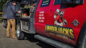 A tree service worker preparing a chainsaw next to a branded truck for Lumberjacks Tree Service in Chattanooga, TN.
