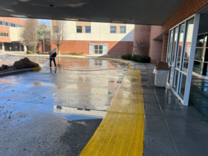 A worker pressure washing a large commercial walkway and entrance area for Selk Solutions in Crossville, TN.