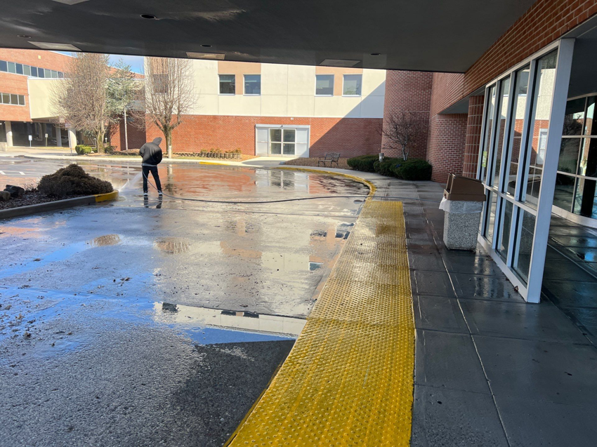 A worker pressure washing a large commercial walkway and entrance area for Selk Solutions in Crossville, TN.