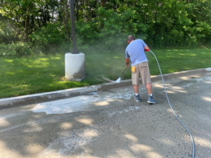 A worker pressure washing a concrete curb and asphalt parking lot for Selk Solutions in Crossville, TN.