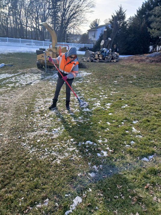 A worker raking wood chips and debris on a lawn after tree service by RJ Robinson Family Tree Service LLC in York, PA