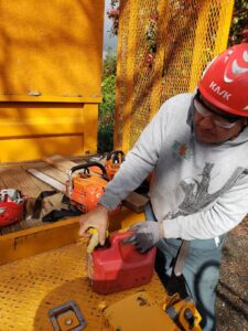 A Dry Leaf Tree Service LLC worker refueling a chainsaw, preparing for tree service work in Sacramento, CA.