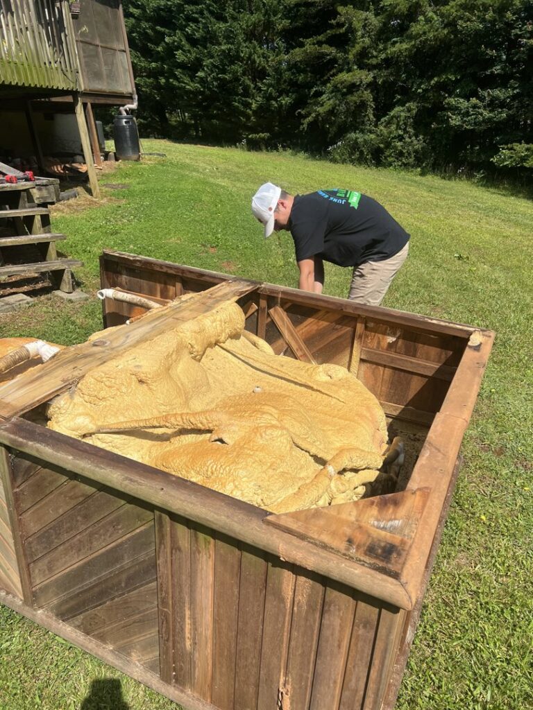 A worker from Barkers Junk Removal & Hauling LLC removing foam from a wooden hot tub in Roanoke, VA.