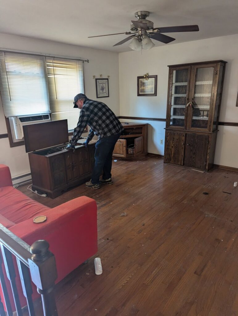 A worker removing an old wooden console during an estate cleanout by Junk Runner, LLC in East Berlin, PA.