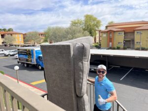 A Happy Hippo Junk Removal worker removing a sofa from a balcony in Scottsdale, AZ.