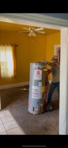 A HaulPros team member using a dolly to remove a large water heater from a room during a junk removal job in Erie, PA.