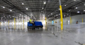 A worker operating a ride-on floor cleaning and polishing machine for Heavy Duty Floors, LLC in New Britain, CT.