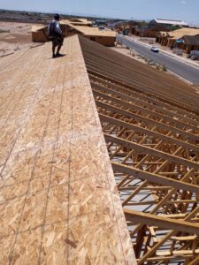 A worker installing OSB sheathing on a roof during construction by AZ Framing and Remodeling in Peoria, AZ