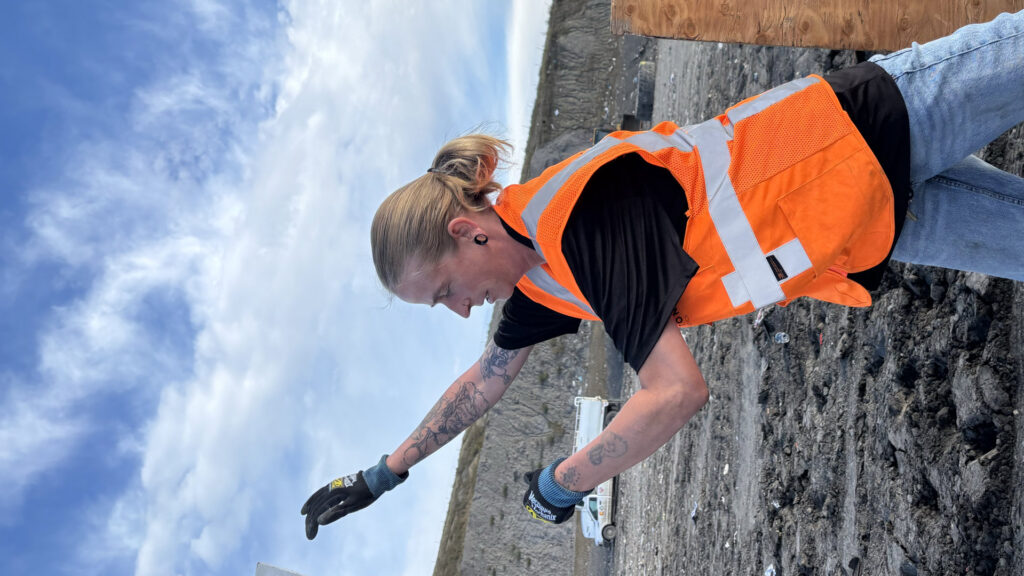 A worker in a safety vest and gloves at a debris removal site for Tiny Monster Junk Removal LLC in Denver, CO.